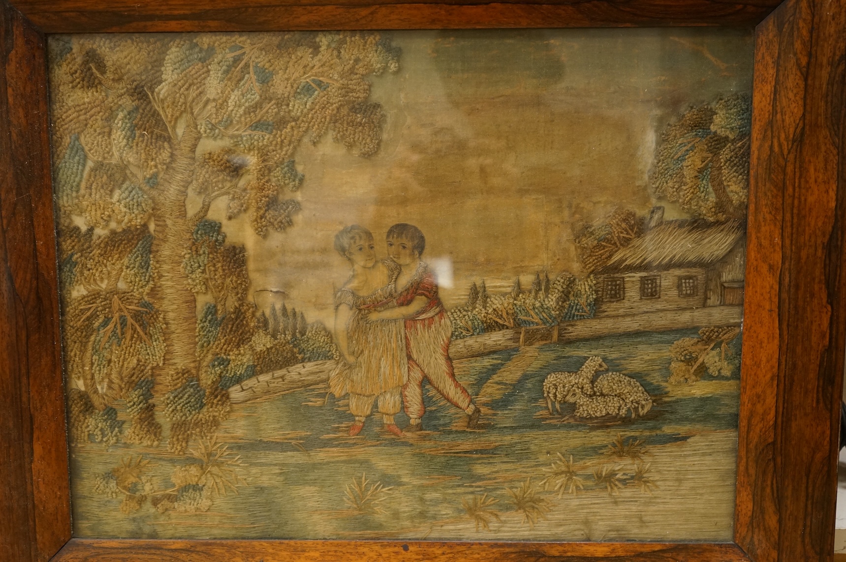 Two early 19th century embroidered silk tapestries depicting figures in landscapes, one framed, largest 52cm high